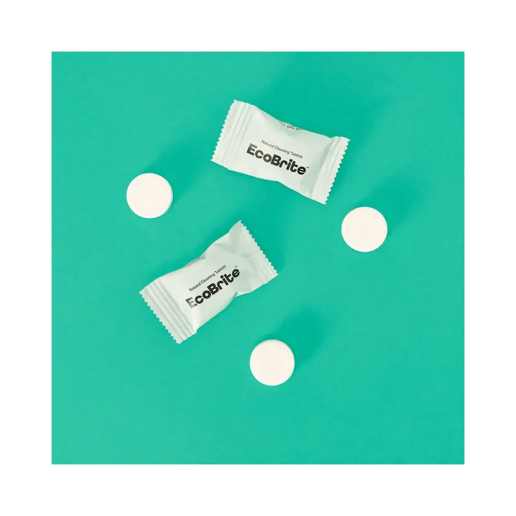 EcoBrite Natural Cleaning Tablets, two individually wrapped tablets and three loose white round tablets arranged on a teal background